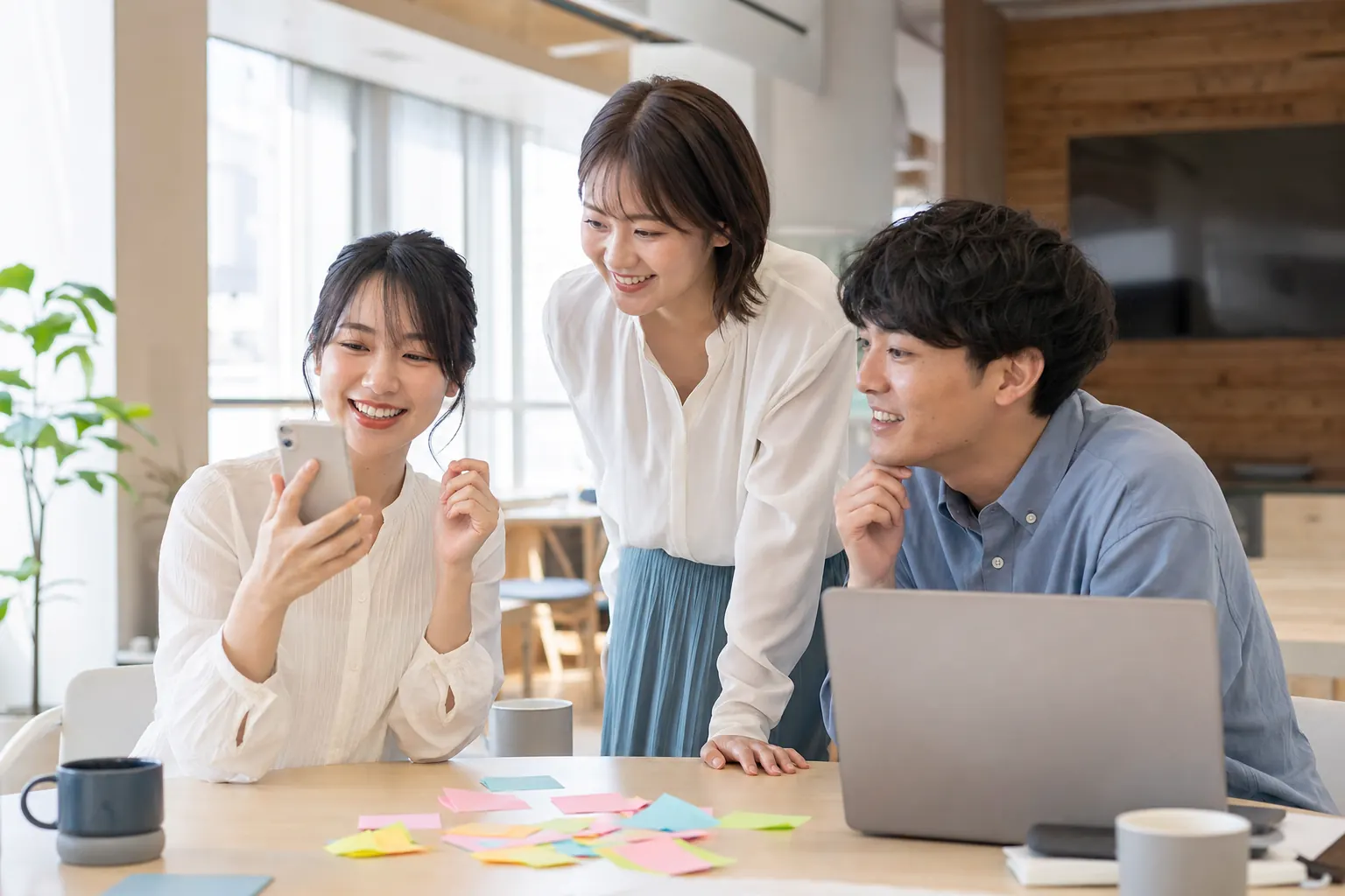 スマートフォンで採用Instagramを見ながら話し合う採用担当者たち